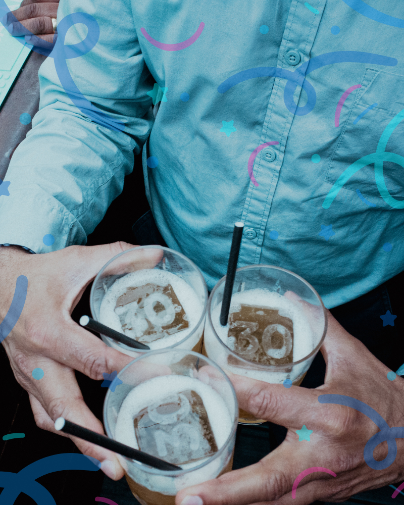guy holding three drinks with 30th ice cubes on them